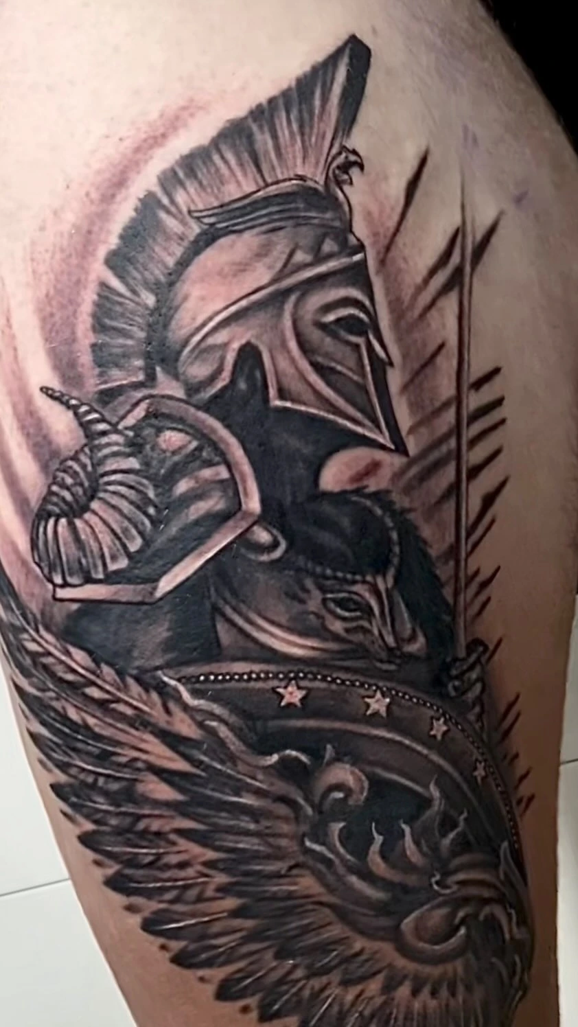 Spartan/Greek warrior with plumed helmet, ram horn shield, wing/feather flourishes and starred banner