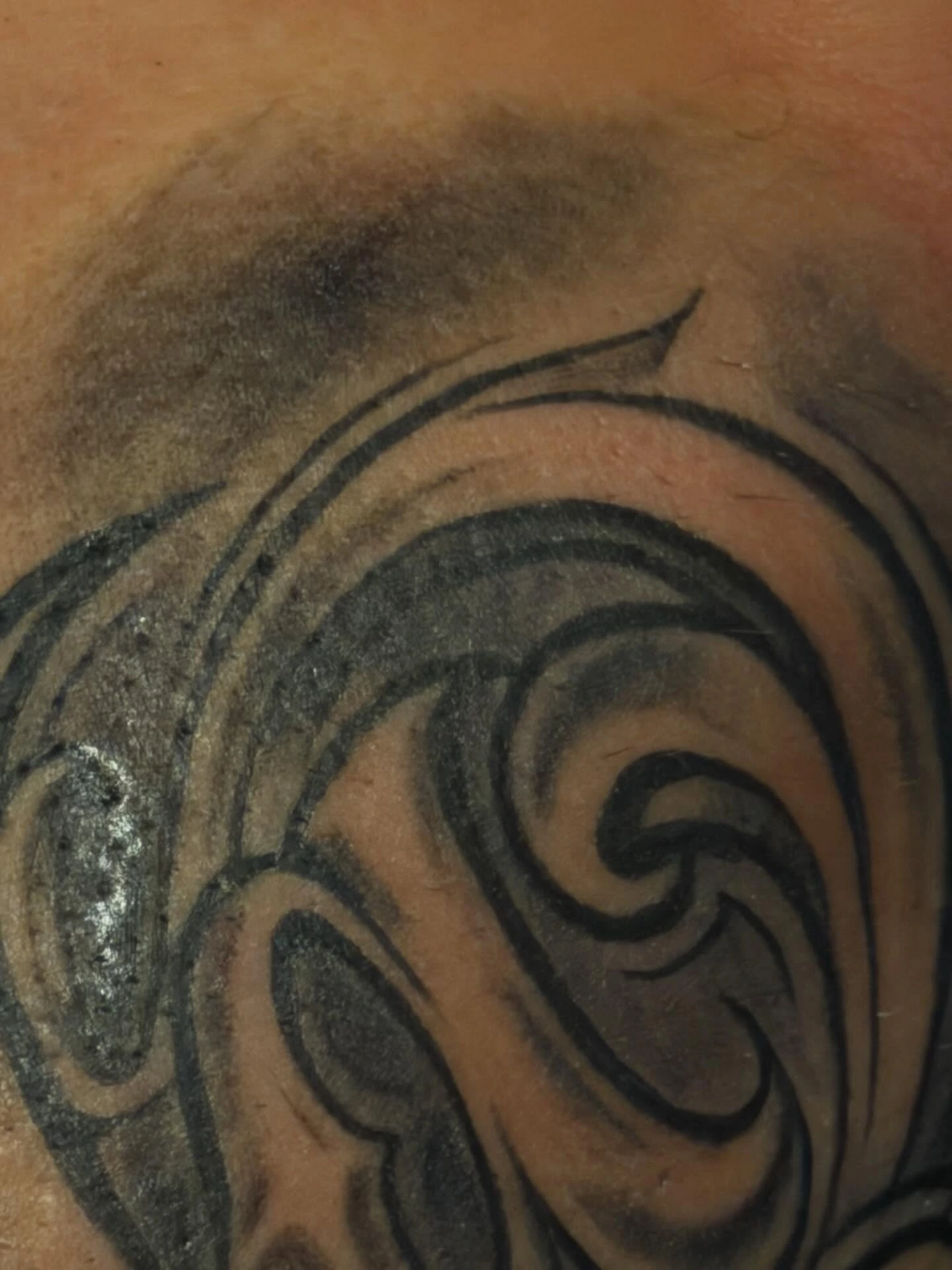 Tribal/script swirl forms on shoulder — partial cropped shot