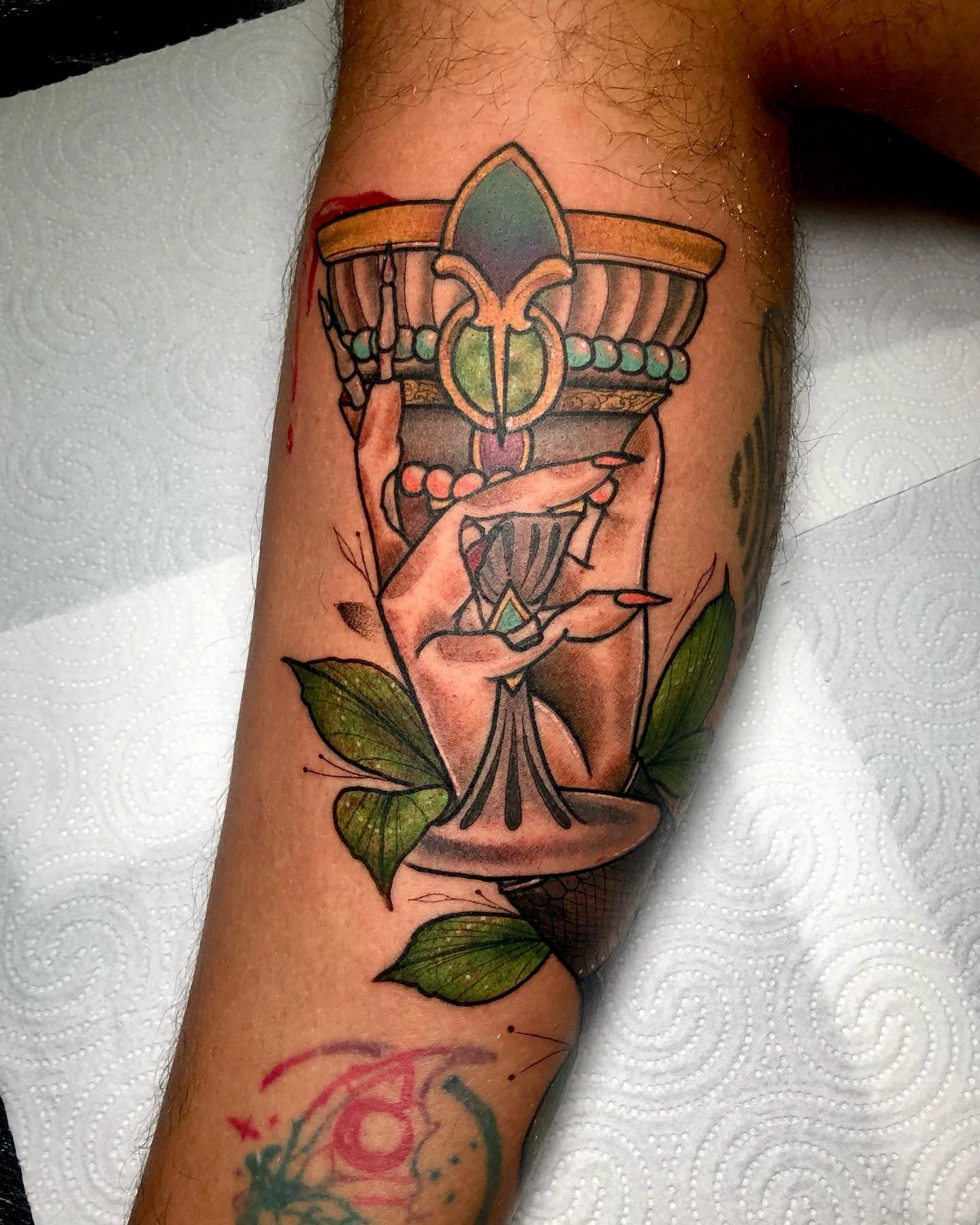 Hand holding jeweled chalice surrounded by leaves