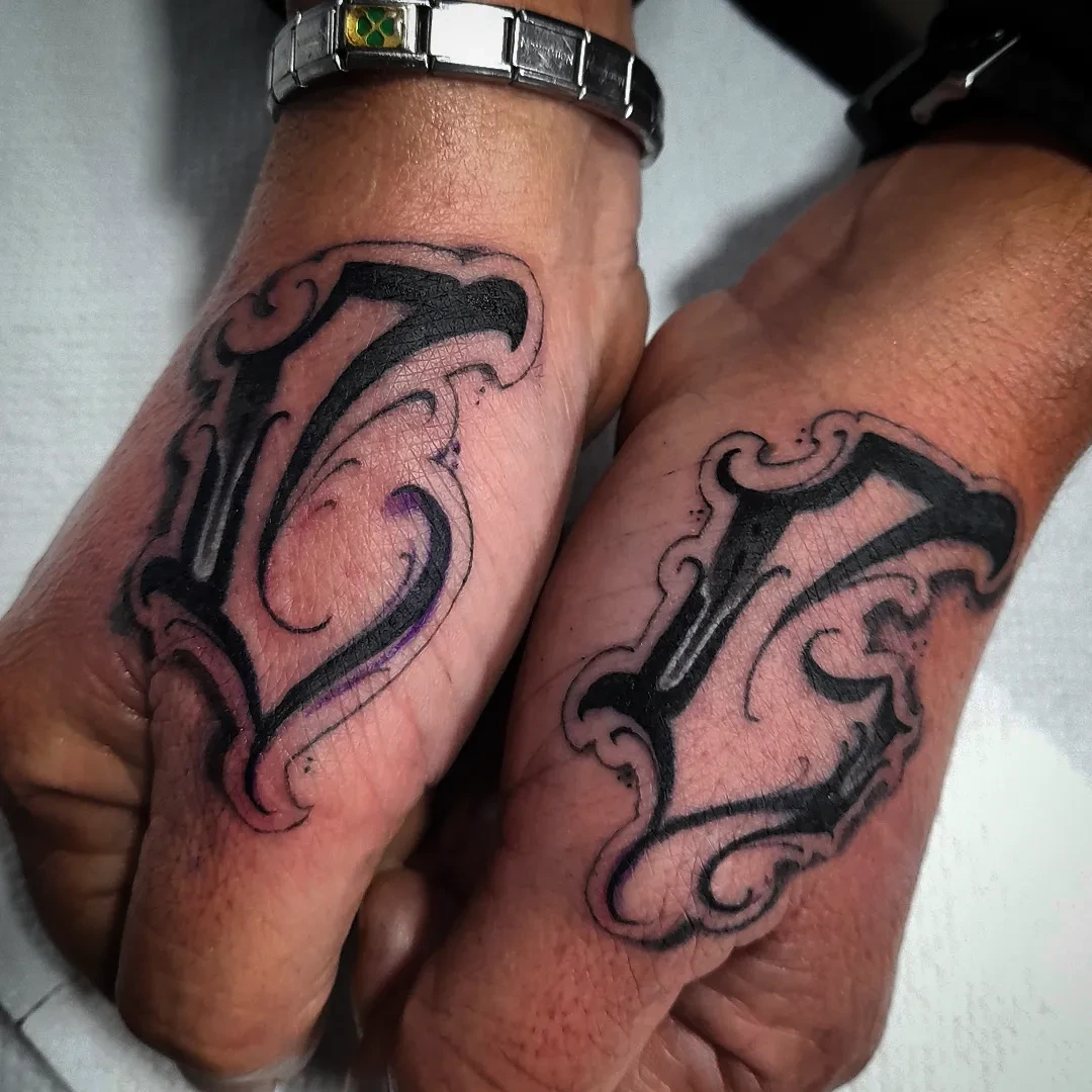 Paired Old English thumb letters 'L' and 'V' (or similar)