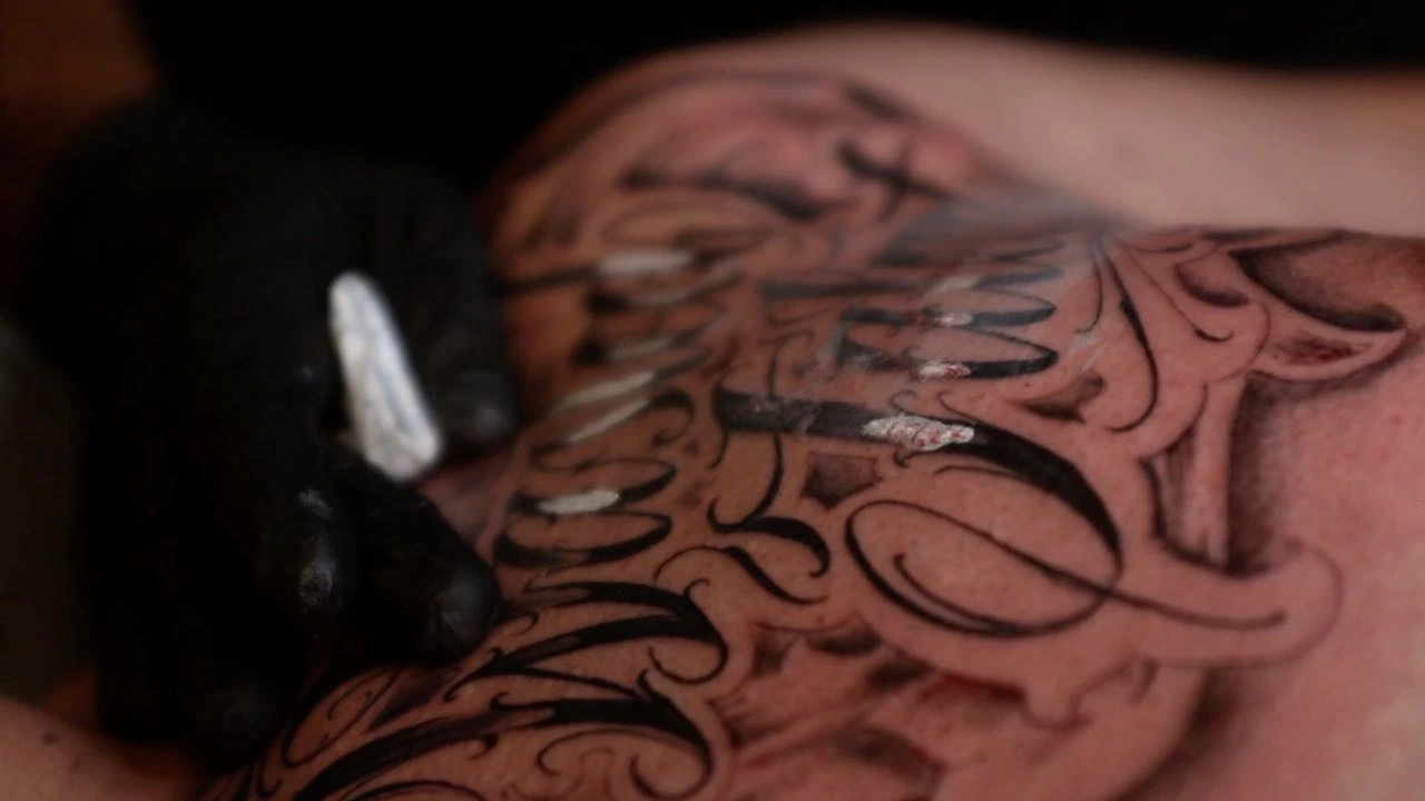 In-progress chicano filigree script (gloved hand, wet skin)