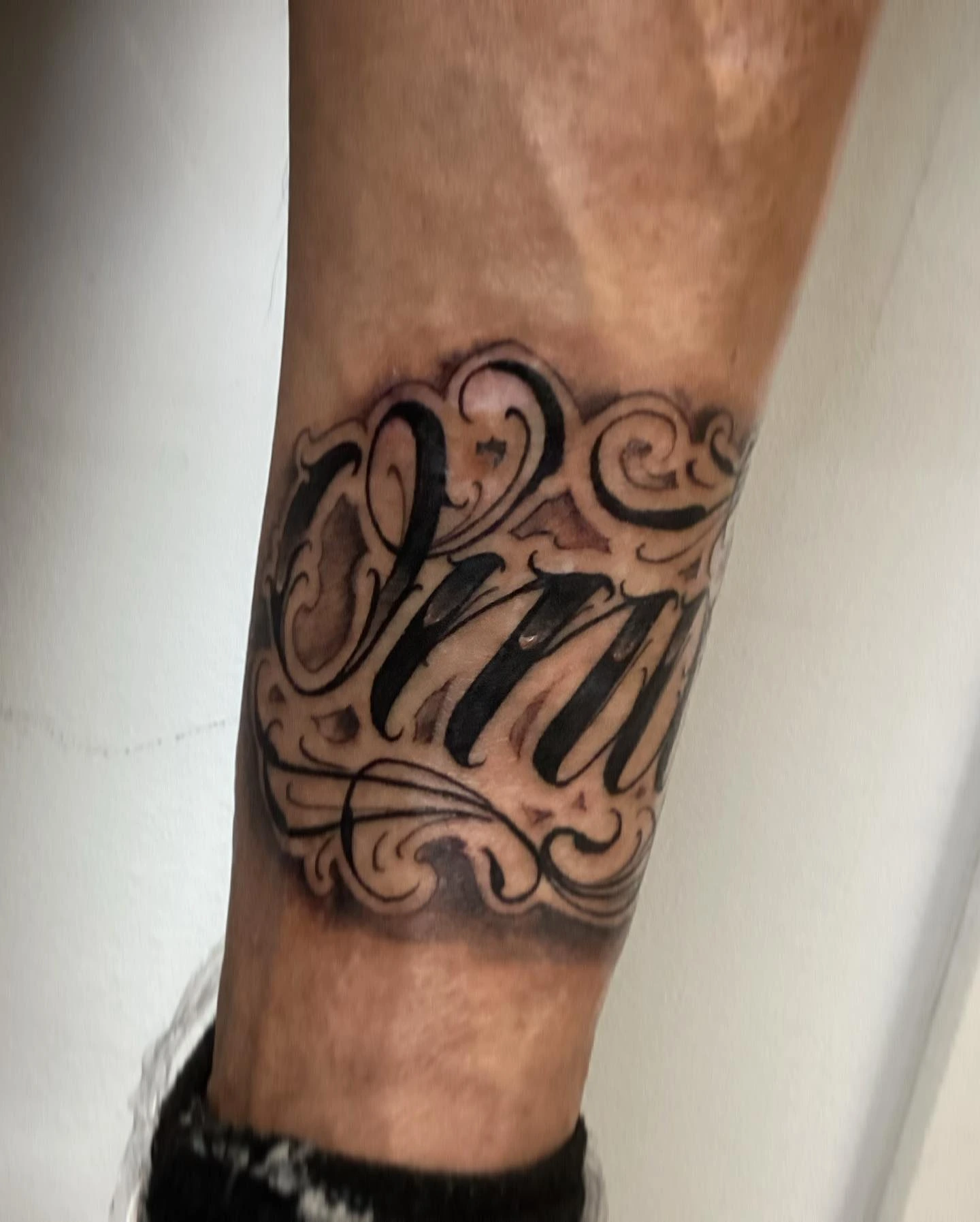 Filigree freehand script lettering on inner forearm