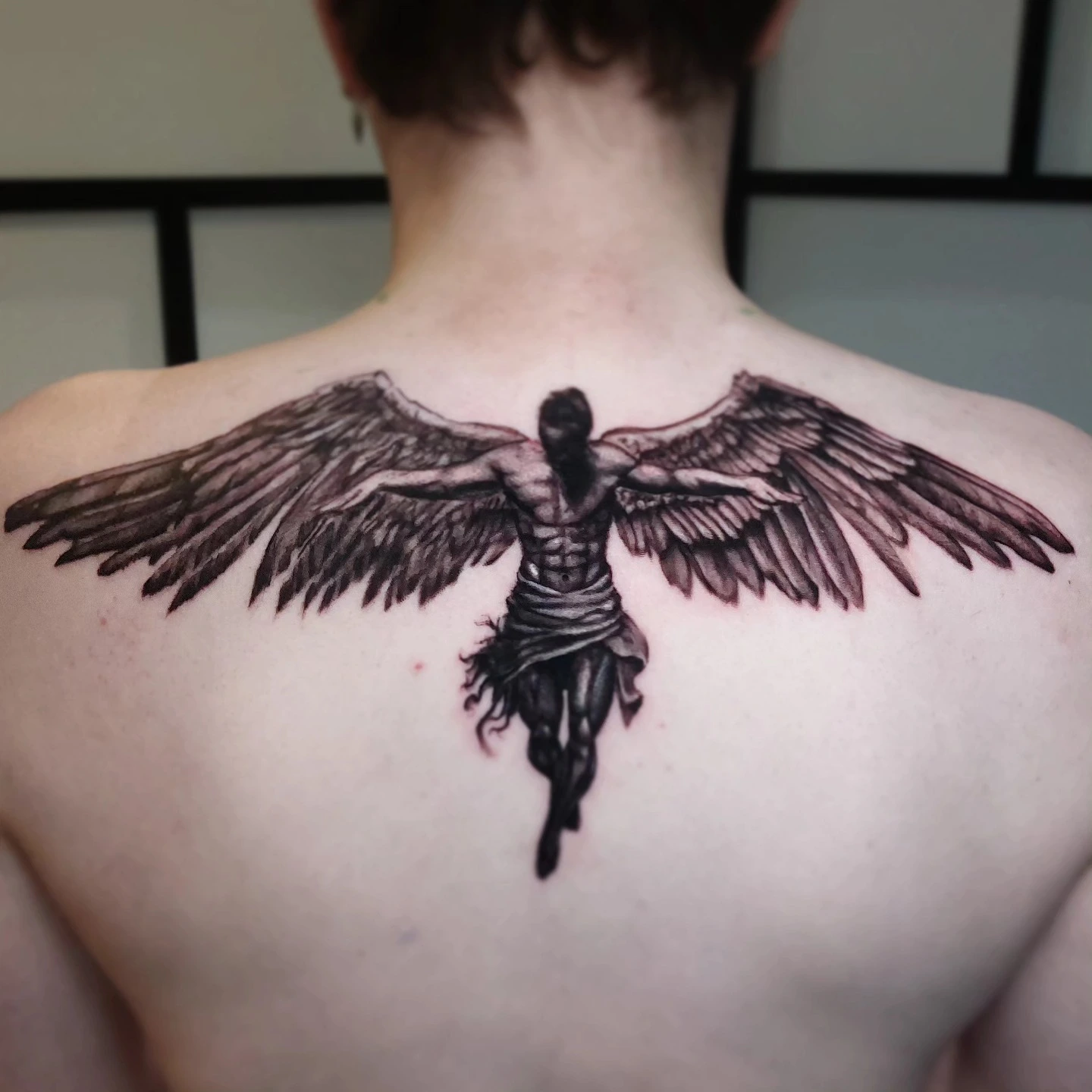 Fall of Icarus / male winged angel with spread wings on upper back