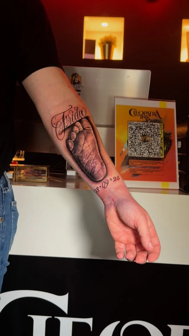 baby footprint with 'Frida' lettering and date, forearm